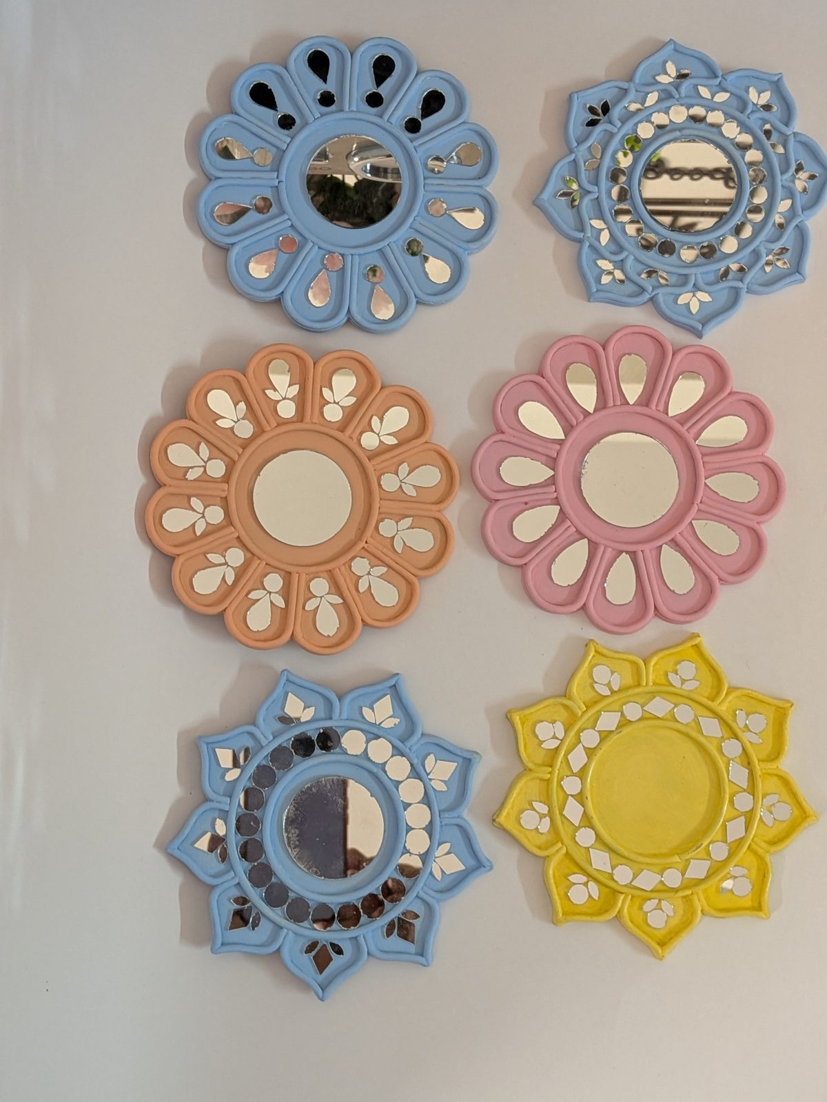 A set of handmade Lippan mirrors in blue, pink, peach and yellow
